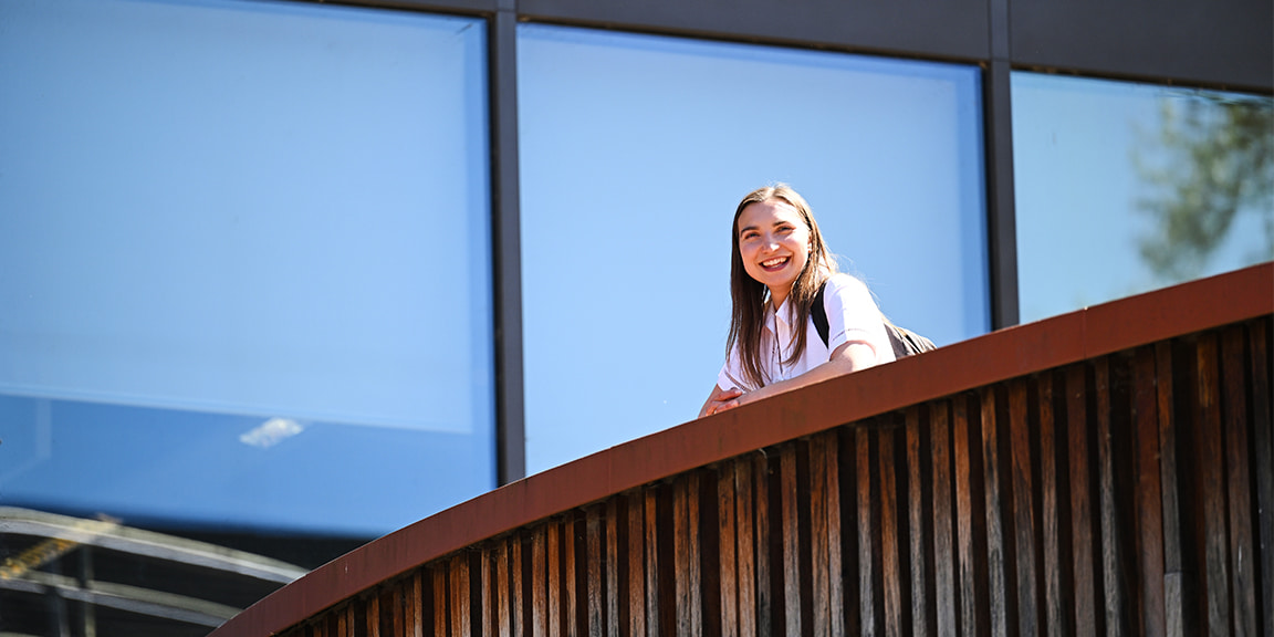 Student smiling and looking down onto the Cambridge campus courtyard