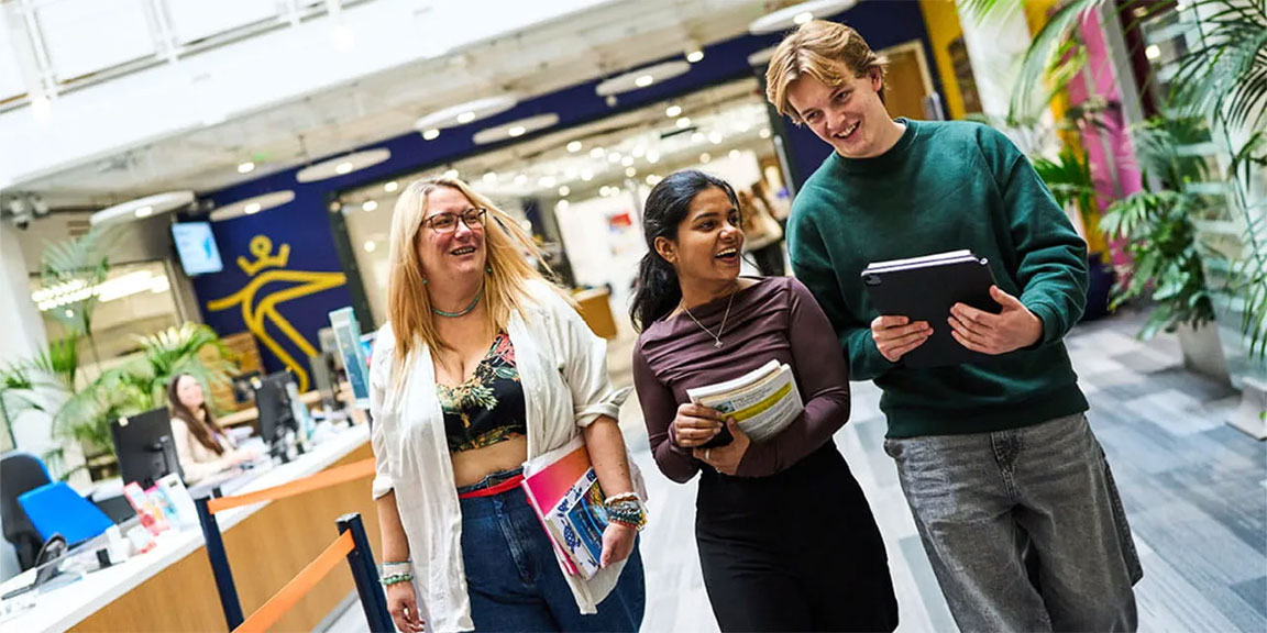 Three students walking through a library