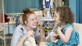 Student nurse talking to a child in a nursing skills lab