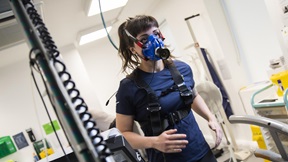 Sport science student running on a treadmill while wearing an oxygen analysis mask