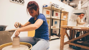 Art and design students using a potters wheel and work bench in a 3D workshop