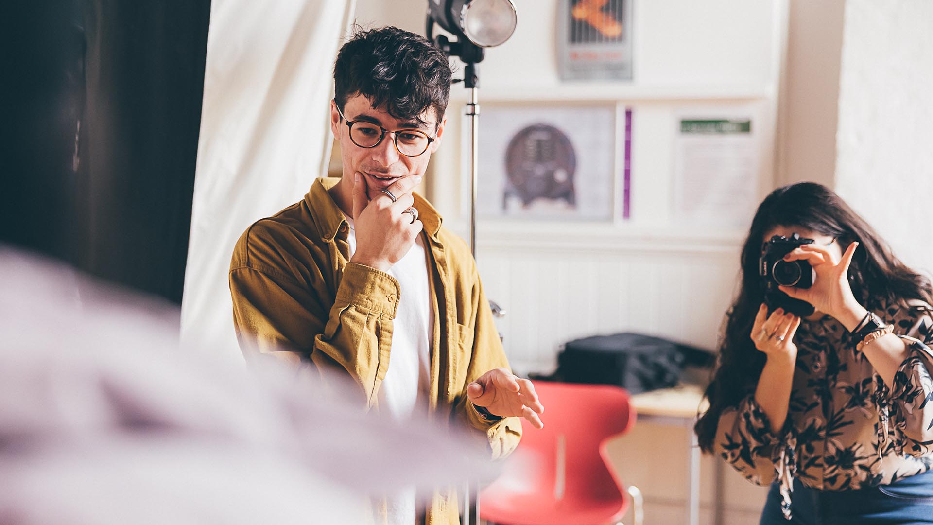 Two fashion students in a studio - one taking photographs and the other art directing