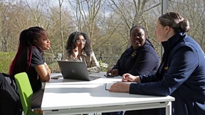 Four students seated at a table in the riverside cafe at ARU Chelmsford