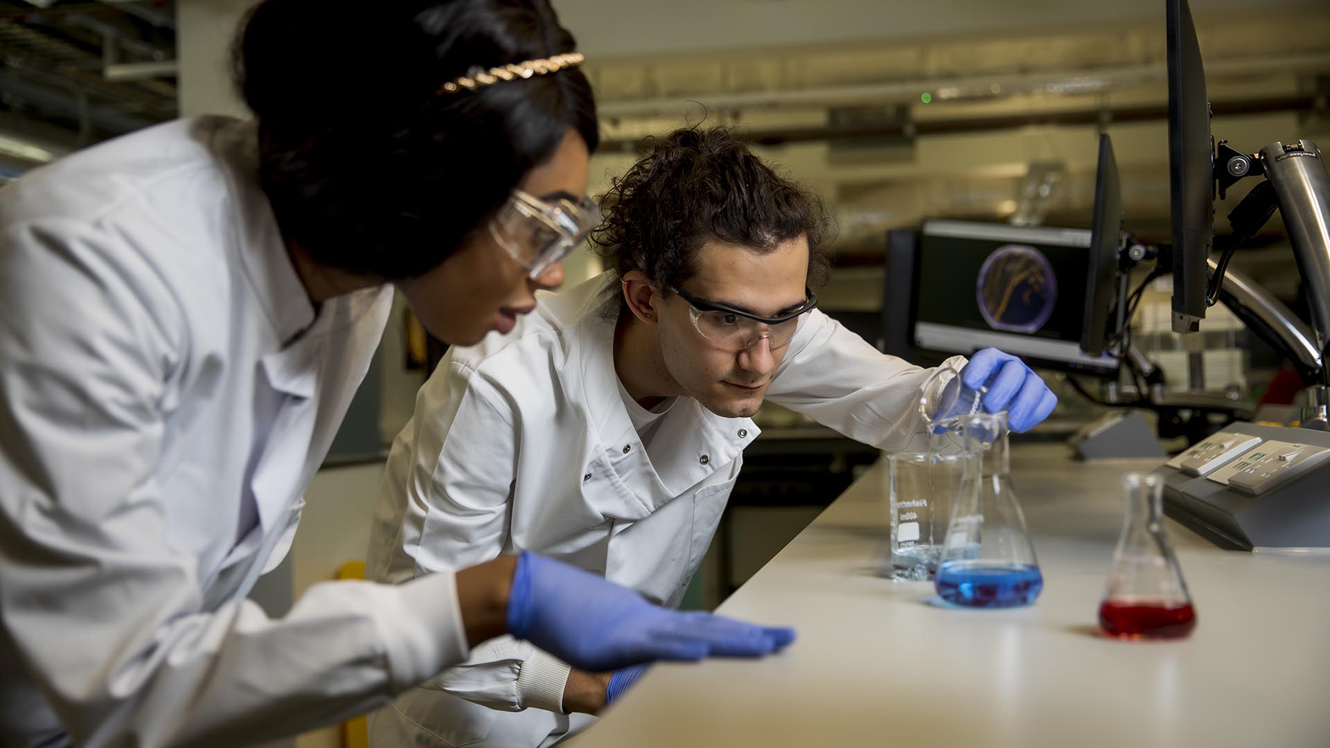 Two students conducting experiments using conical flasks in a medical science Superlab