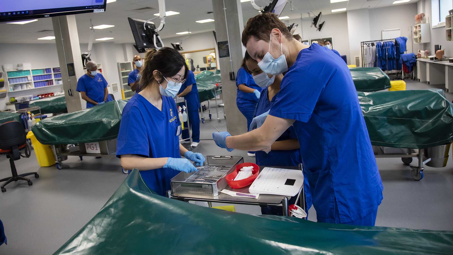 Students wearing surgical scrubs and working in the Anatomy Suite at the School of Medicine, ARU Chelmsford