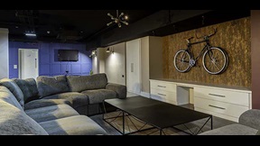 Sofas around a low table, with a bike hanging on the wall and a TV in the distance, in Cambridge's CB1 accommodation