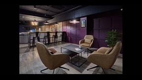 Armchairs around a low table, with a breakfast bar and sofas in the distance, in Cambridge's CB1 accommodation