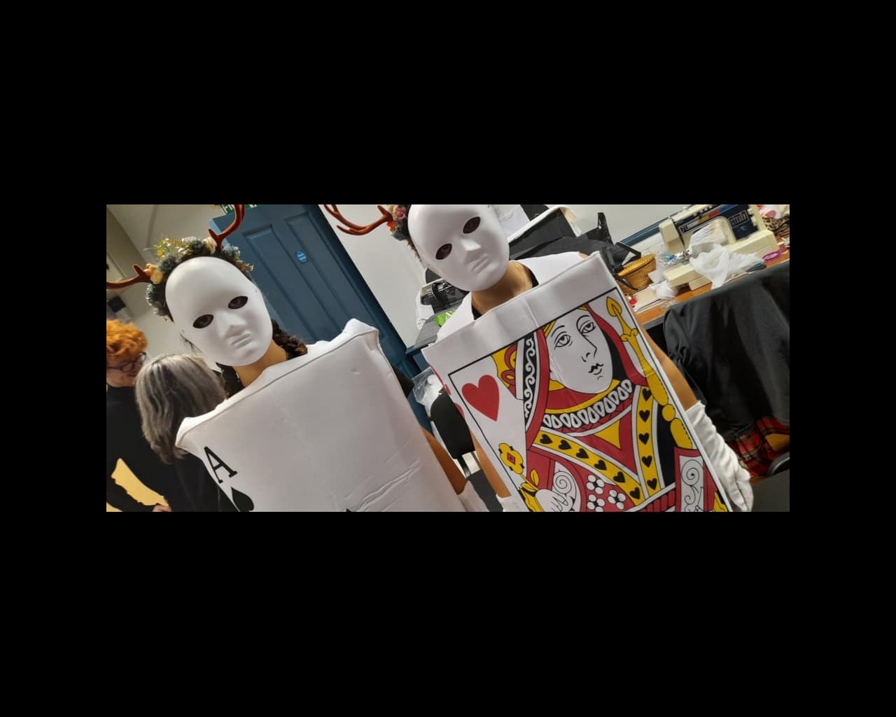 Two students dressed as playing cards with white masks and antlers
