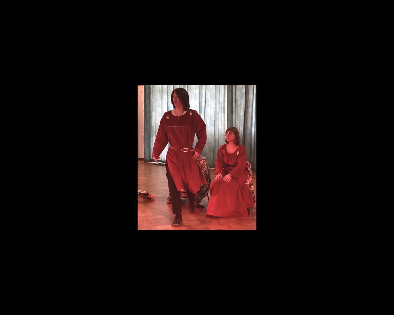 Two drama students in red Chinese-style costumes rehearsing a play