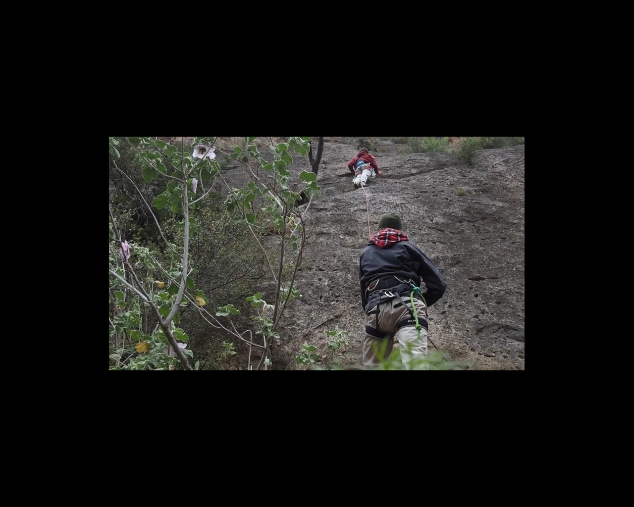 Film still of two men climbing rockface