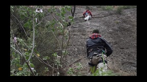 Film still of two men climbing rockface