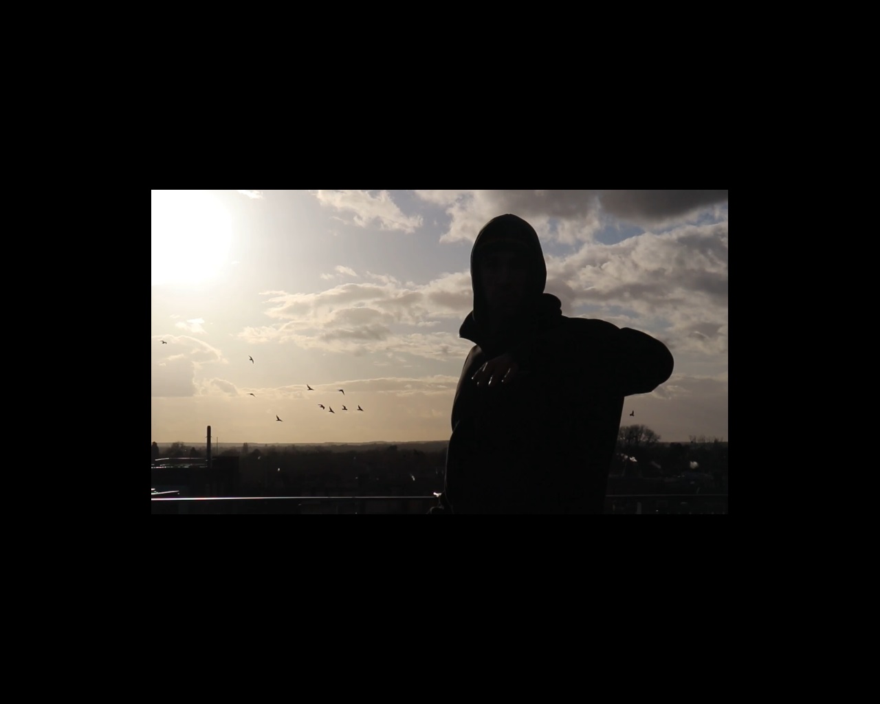 Film still of man dancing on rooftop at sunset