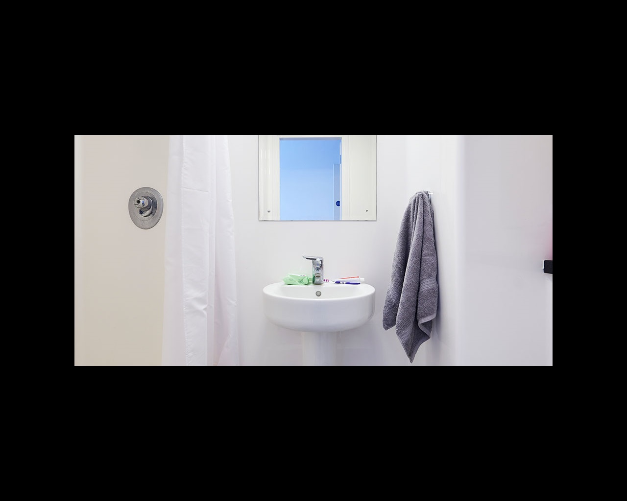 Detail of shower room showing shower curtain and basin