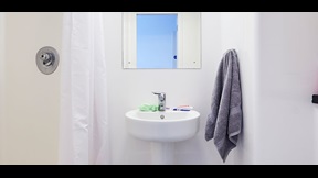 Detail of shower room showing shower curtain and basin