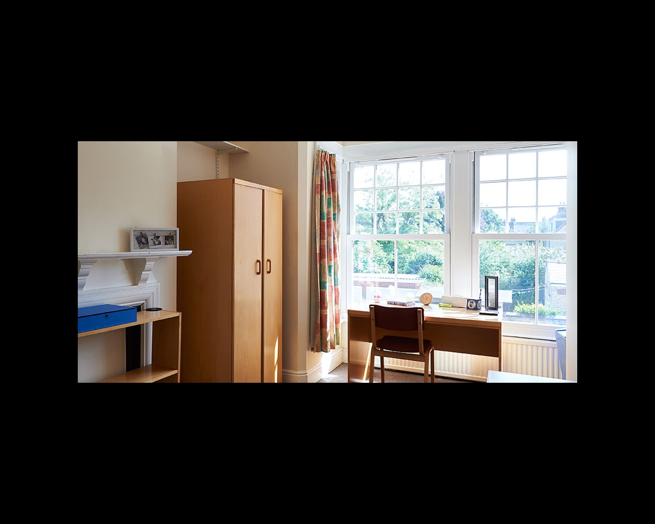 Wardrobe, desk and chair in front of windows